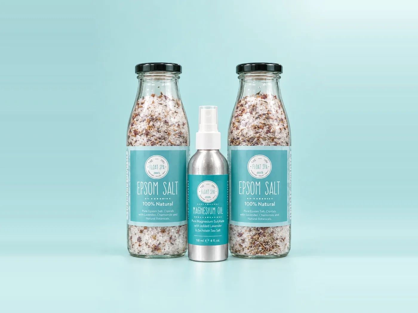 The Float Spa Epsom Salt bottles and magnesium oil spray on a soft aqua background